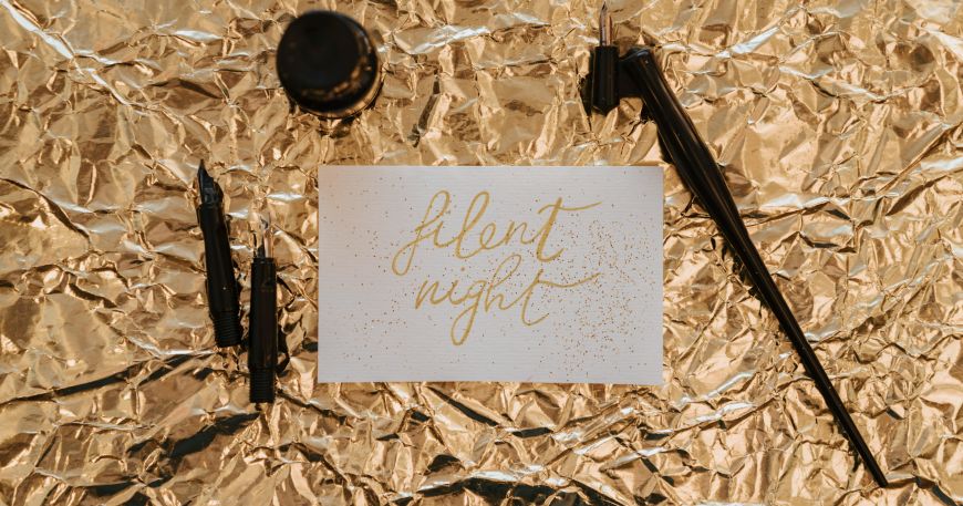 A note written in ink of a metallic gold colour rests on top of foil with a metallic gold finish.
