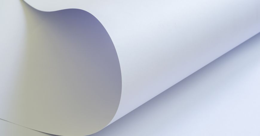A large sheet of paper curled up at the end to show the smooth clay coated surface. 