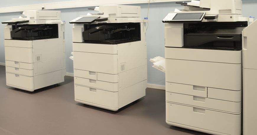 A set of three copiers in an office space.
