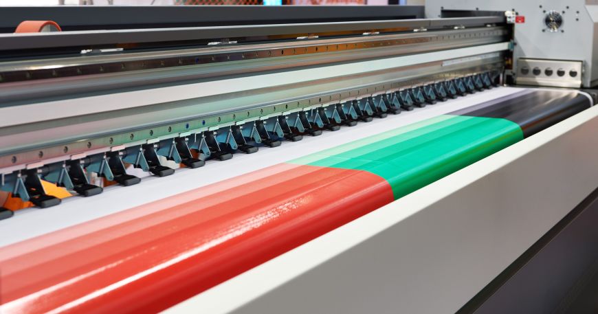 A large format plotter printer printing a coloured design; it is especially important for large format items that the materials used have good coverage.
