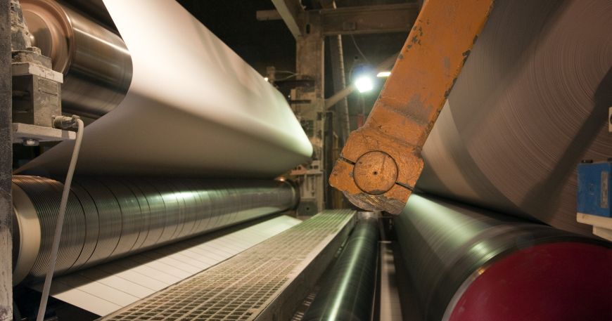 Paper being manufactured in a paper mill; the paper must remain stable as it is processed by a series of rollers.