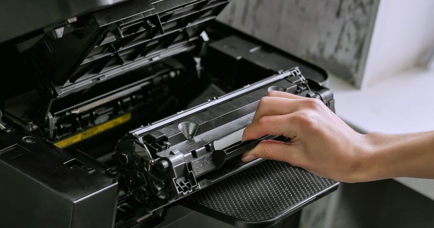 A laser printer with its cover open; the fuser unit is visible towards the back of the printer with its yellow label.