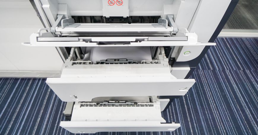 Three open trays of an office printer; the bottom two are standard paper trays, while the top one is a media bypass tray.