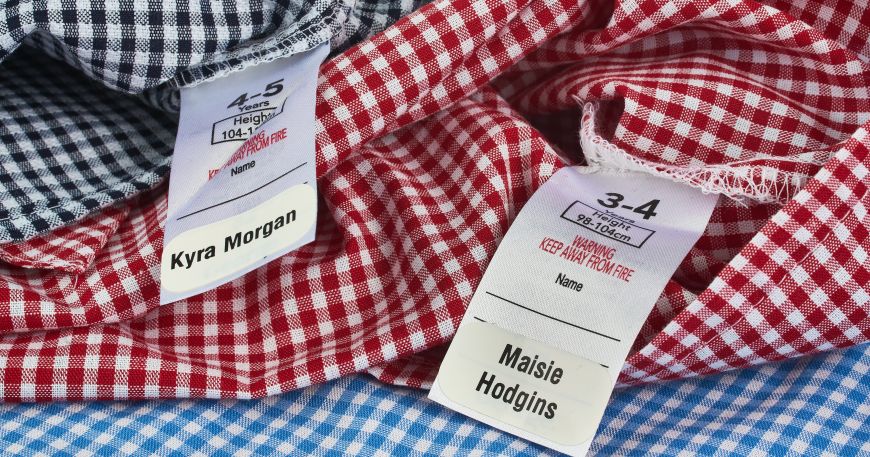 Two school dresses with name labels stuck onto the wash-care label of each garment.