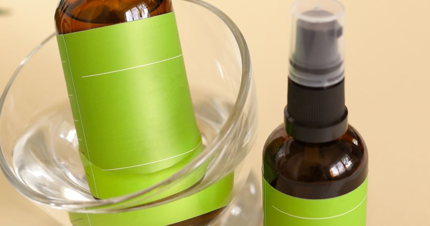 Two cosmetic product bottles that have been labelled using a green overlap label. Each label extends around the whole label before overlapping itself (on the left hand side of each bottle).