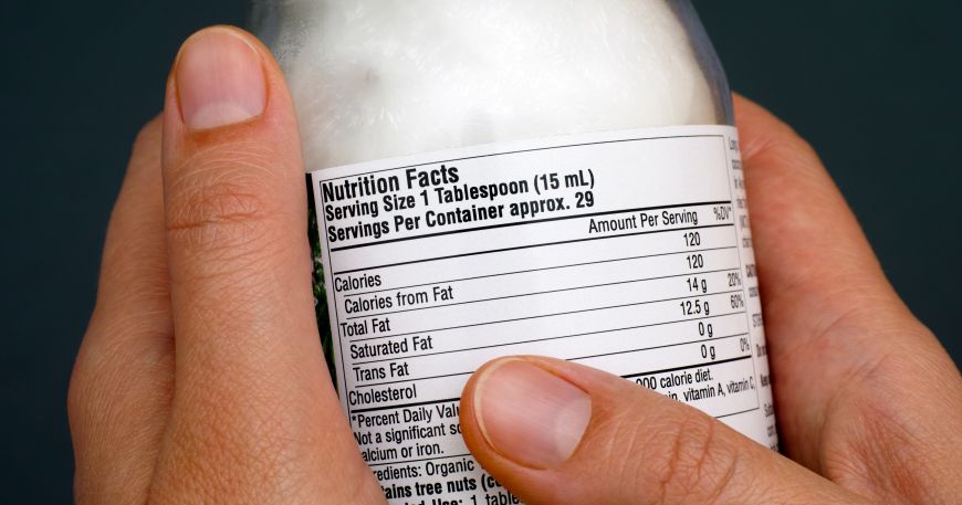 A person holding a jar of food; there is a packaging label on the back of the jar, which displays nutrition facts and ingredient information.