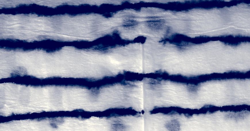 Penetration of indigo dye through a white material; the dye from a lower layer (dots) has begun to penetrate through to the top layer (where the dye has been applied in lines).