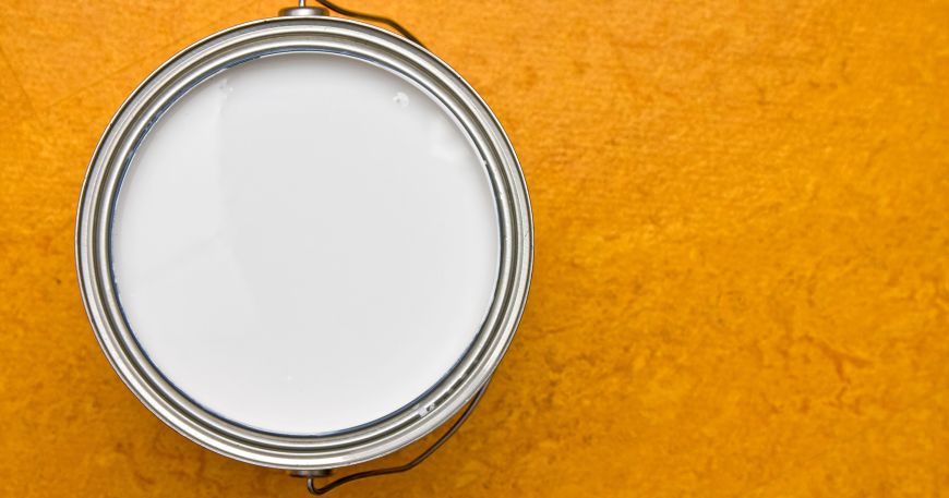 A tin containing a white primer sitting on an orange surface.