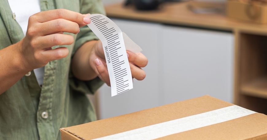 A person removes a label from its release liner or backing sheet; the label is on the left, while the release liner is on the right.