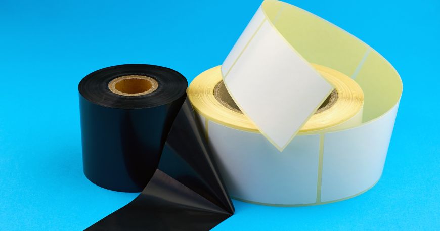 A roll of labels and a roll of ribbon; a ribbon used for printing is a thin band of material that carries a printing ink or pigment.