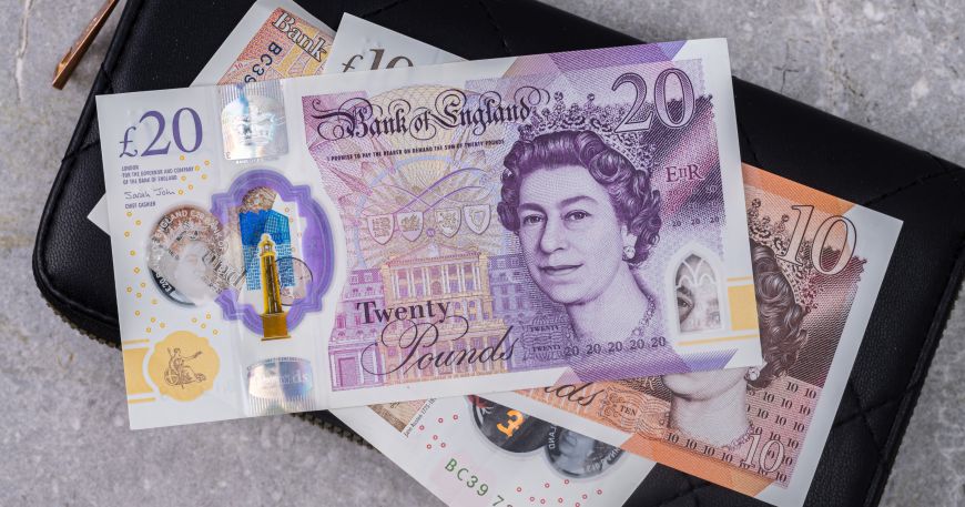 A set of UK bank notes sitting on top of a wallet; UK bank notes use various forms of security printing to protect against counterfeiting.