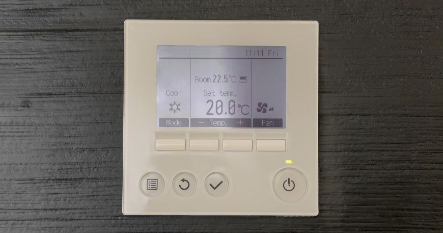 A thermostat mounted on a black wall showing the room temperature; the recommended service temperature gives the range of temperatures that a label can be exposed to once it has been applied to an item.