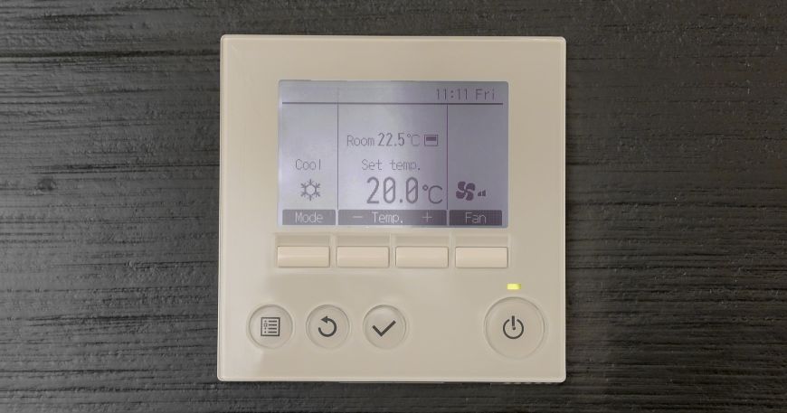 A thermostat mounted on a black wall showing the room temperature; the recommended service temperature gives the range of temperatures that a label can be exposed to once it has been applied to an item.