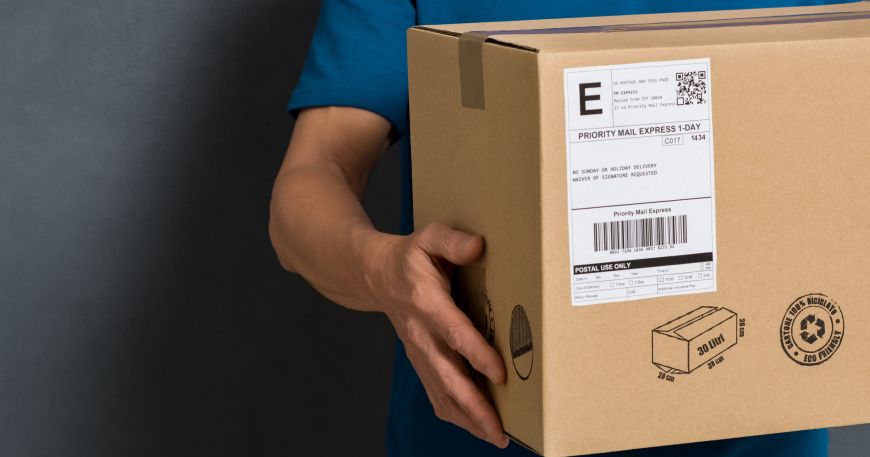 A person holding a parcel that has been labelled with a shipping label.