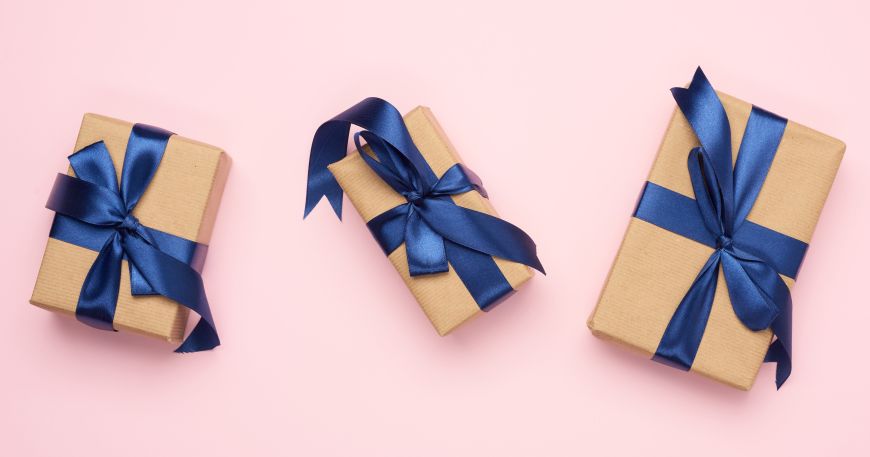 Three gifts wrapped up in brown wrapping paper and a blue ribbon; the ribbon has a silk finish, while the paper has a matt finish.