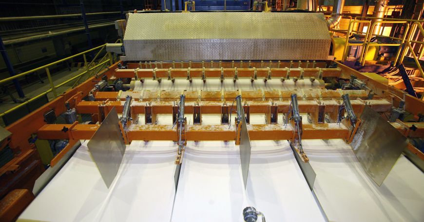 A paper web being cut into three strips at a factory; materials used to make labels need good stability to ensure they maintain their characteristics and properties throughout manufacturing, printing, and their final application.