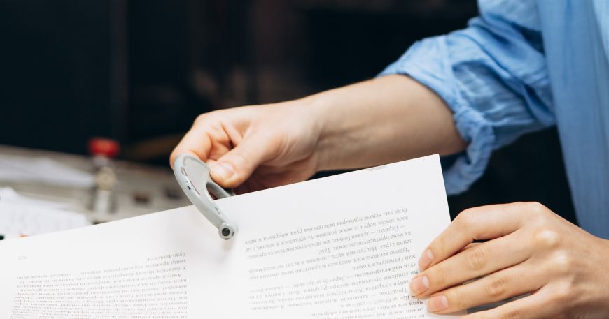 A person uses a micrometer to measure the thickness of a sheet of paper.