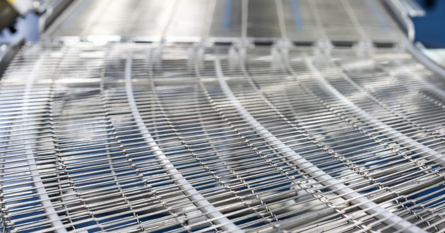 A stainless steel wire mesh belt in a factory; the wire side of paper is the side that was in contact with the wire belt during manufacturing.