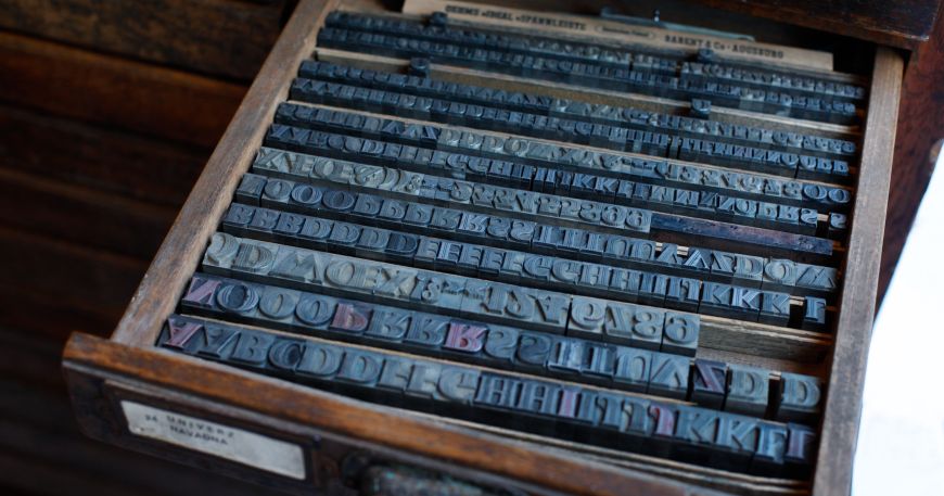 A drawer containing several sets of metal blocks used for letterpress printing. Each set is for the same size (font) of a particular design (typeface).