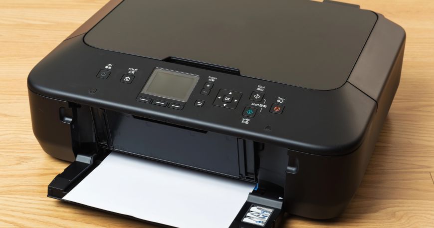 A desktop printer sitting on a wooden table; both laser and inkjet desktop printers use forms of non-impact printing.