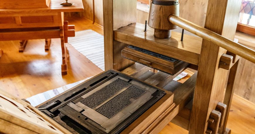 A wooden letterpress printer, which uses a type of analogue printing to produce copies of an original image (here a block of text).