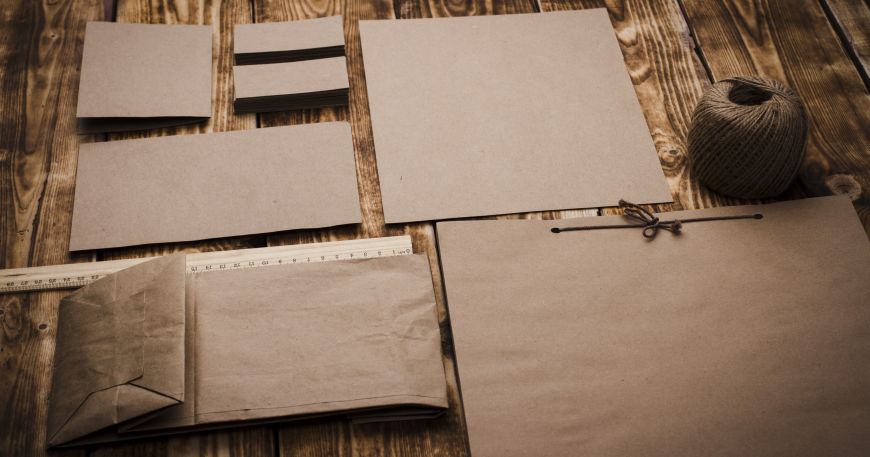 Examples of items made from Kraft paper; a set of Kraft bags, sheets, and cards arranged on a wooden floor.