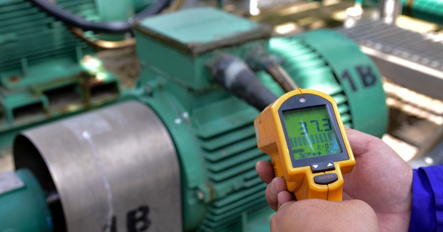 A worker measures the temperature of a motor with an infrared thermometer. All labels have an application temperature, which refers to the temperature of the label and item being labelled during the application process.
