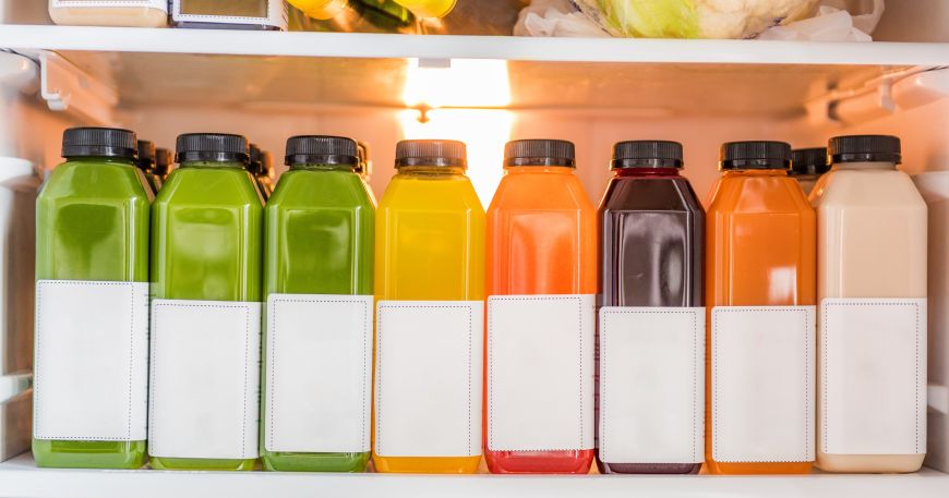 A range of drinks bottles in a fridge, each labelled with a white label. Cold temperature adhesives are designed to withstand cold temperatures such as those in refridgerators.