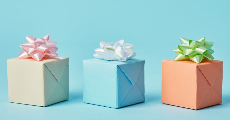 Three presents wrapped in paper with a decorative bow each; the wrapping paper has a dull matt finish, while the bows have a shiny gloss finish.