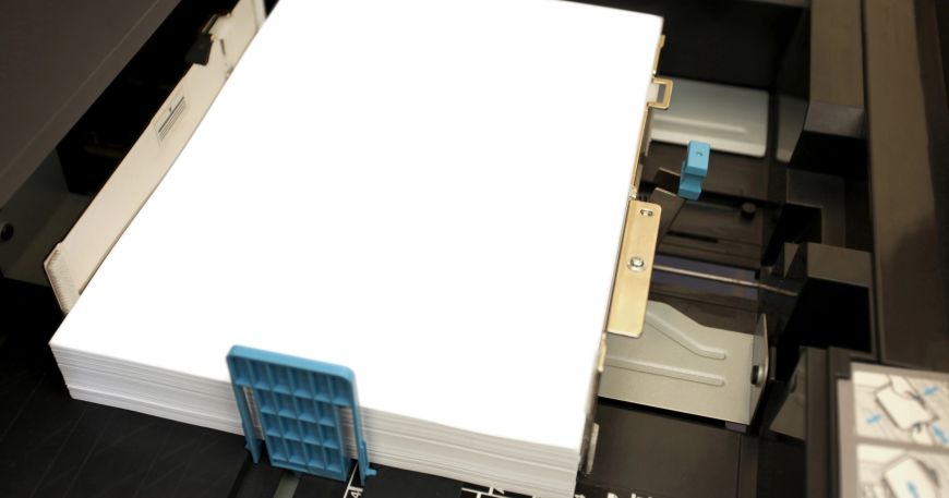 A ream of A4 paper in a printer tray; the density of paper is the mass per unit area.