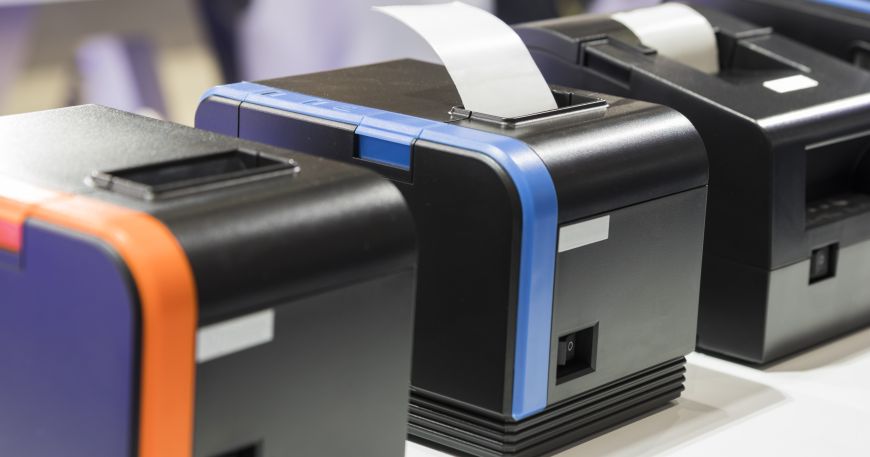 A row of direct thermal printers; two of the machines have been loaded with thermal rolls ready for printing.