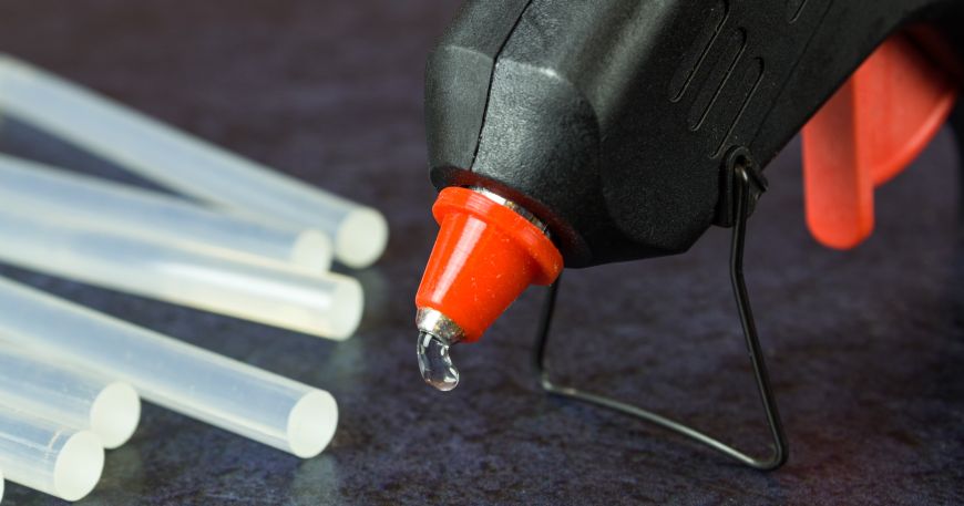 A glue gun with glue sticks; glue sticks are one of the most common types of thermoplastic adhesive.