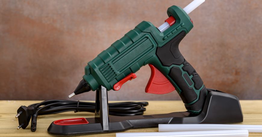A hot melt glue gun and two glue sticks; glue sticks are the most common example of a hot melt adhesive. 