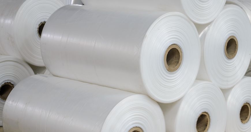 Stacks of rolls of white polyolefin film in a warehouse. 