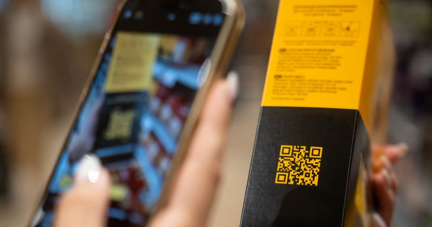 A woman uses her smartphone to scan a QR code or 2D barcode that has been printed onto product packaging.