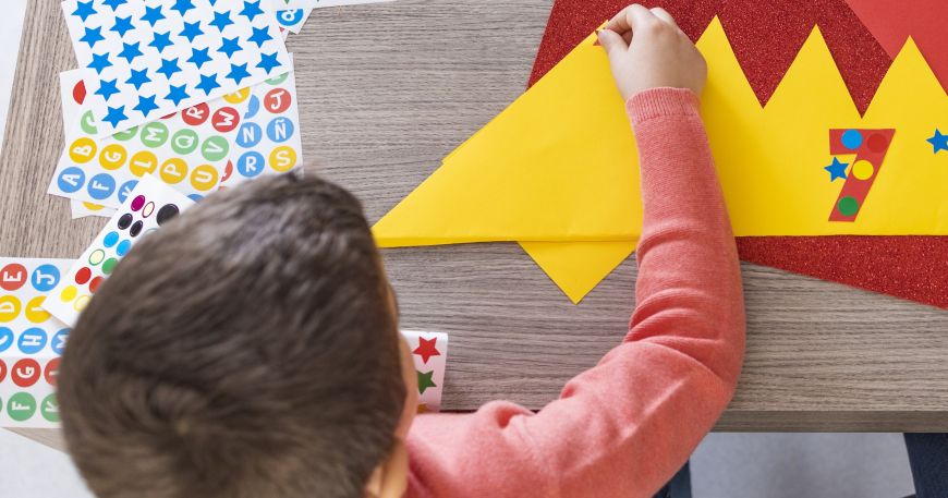 A boy applies stickers onto bright yellow paper; the stickers have high instant adhesion, which means they stick immediately onto the paper.