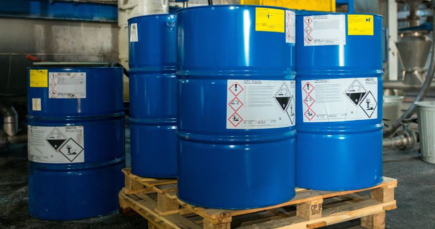 A set of chemical barrels in a warehouse; each barrel has been labelled with a number of permanent labels.